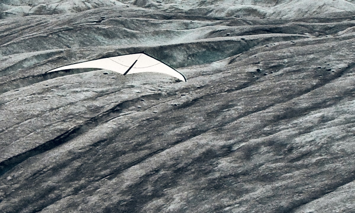 A white kite rising slowly over the glacier.