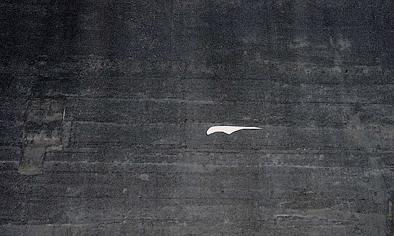 Weisser Drachen fliegt sehr hoch vor dunklem Staudamm, Engadin.