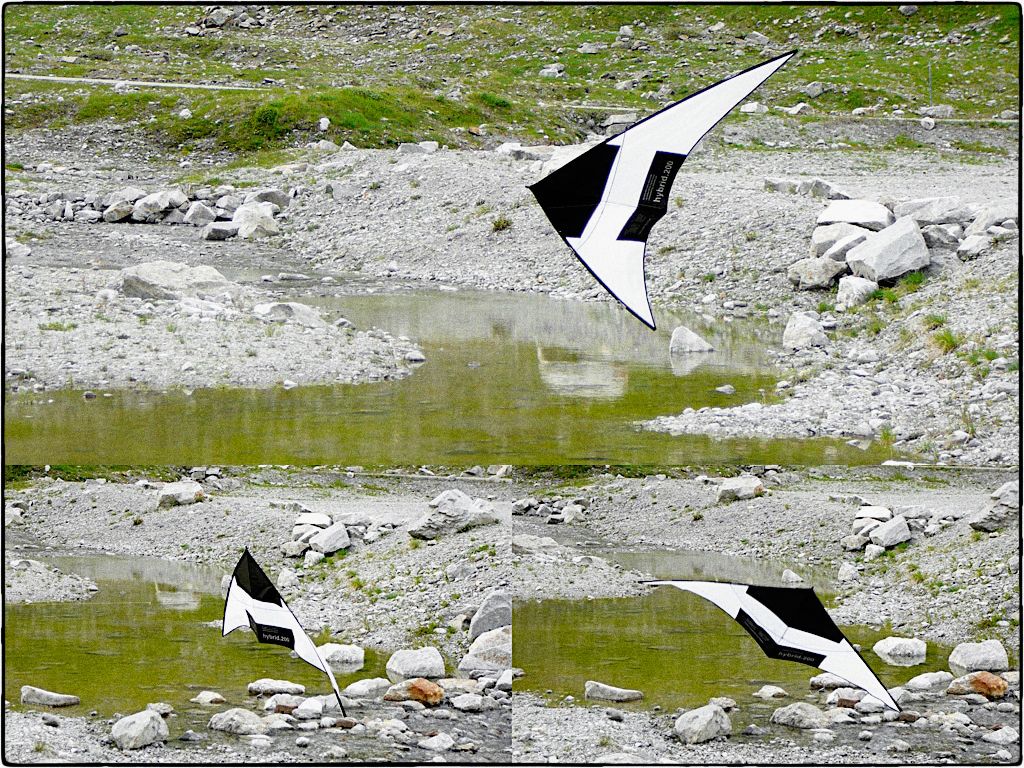 A hybrid 200 kite floating near to the ground above a stone flatland.